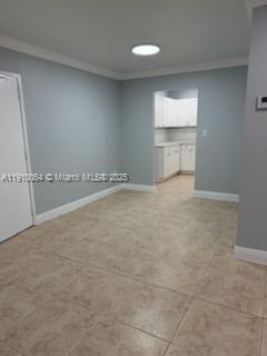 A room with light-colored tile flooring leads into a kitchen with white cabinets — 1805 W 56th St # 412, Hialeah FL 33012, HIALEAH, FL