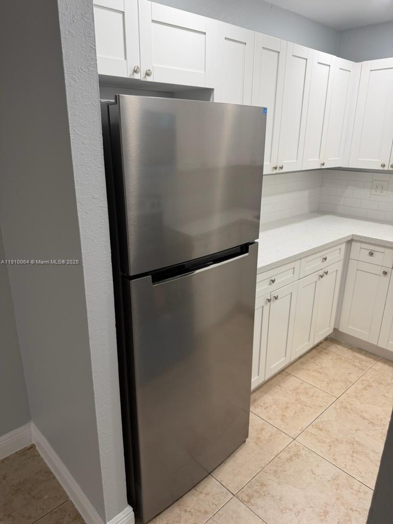 A stainless steel refrigerator stands in a kitchen with white cabinets and tiled floors — 1805 W 56th St # 412, Hialeah FL 33012, HIALEAH, FL