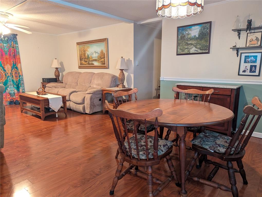 A living room and dining area with wood flooring, a beige sofa, and wooden furniture — 526 CASSANDRA LANE, LAKELAND, FL