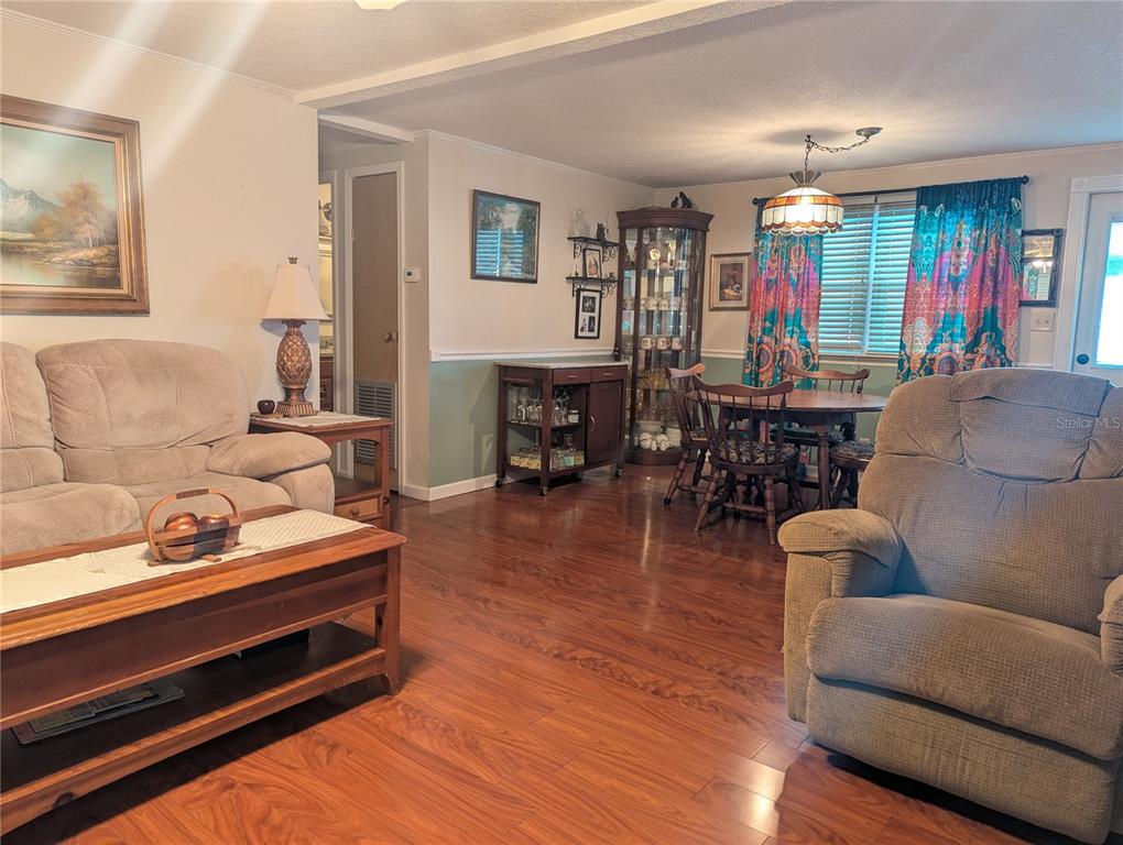 A living and dining area with wood-look flooring, a beige sofa, and a dining set — 526 CASSANDRA LANE, LAKELAND, FL