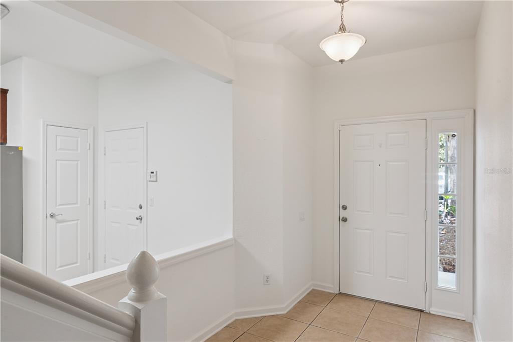 An entryway features tile flooring, a white front door with a sidelight, and a staircase — 6887 SPERONE STREET, ORLANDO, FL