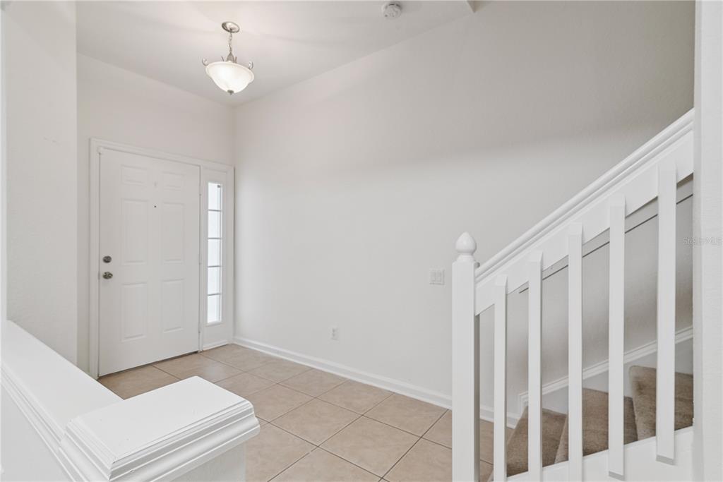 A bright entryway features white walls, tile flooring, a front door, and a staircase — 6887 SPERONE STREET, ORLANDO, FL