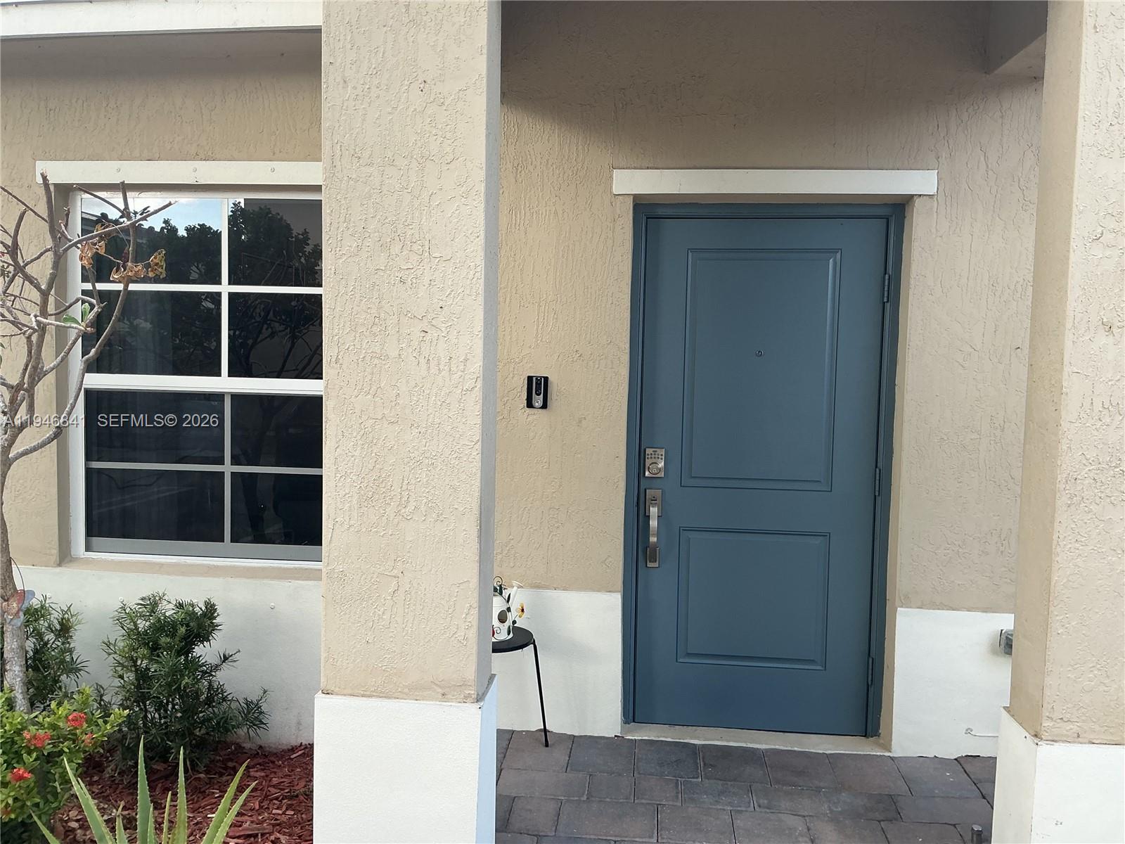 A blue front door with a keypad lock sits beside a window and pillar — 484 NE 4th Ave, Florida City FL 33034, FLORIDA CITY, FL