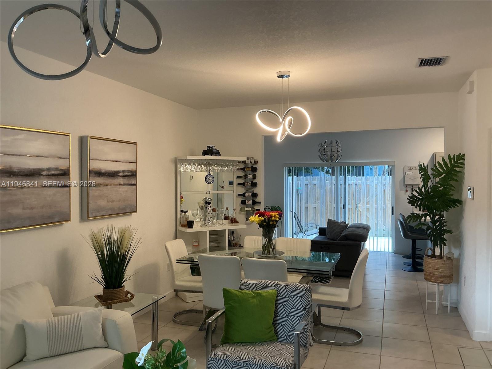 A dining area features a glass table, white chairs, a bar unit, and modern lighting — 484 NE 4th Ave, Florida City FL 33034, FLORIDA CITY, FL