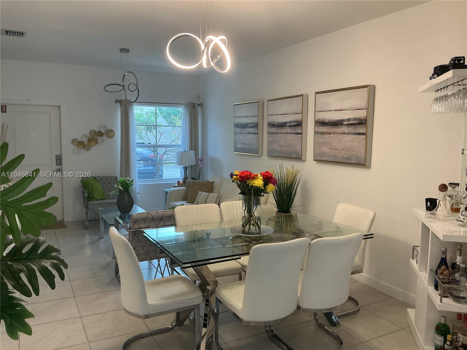 A dining area with a glass table and white chairs sits adjacent to a living space — 484 NE 4th Ave, Florida City FL 33034, FLORIDA CITY, FL