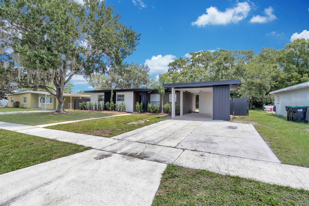 A single-story house with a flat roof, carport, and concrete driveway under a blue sky — 1007 EGAN DRIVE, ORLANDO, FL