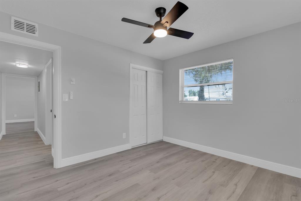 A bedroom with light gray walls, wood-look flooring, a ceiling fan, and a sliding closet — 1007 EGAN DRIVE, ORLANDO, FL