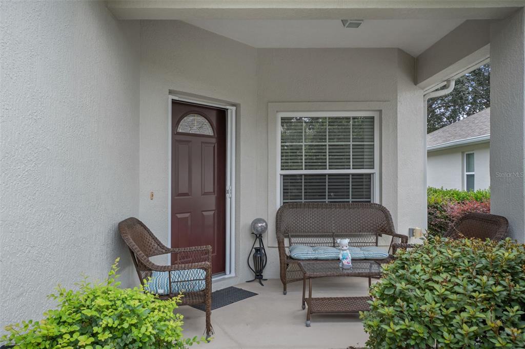 A covered front porch features a brown door, a window, and wicker patio furniture — 6531 W CANNONDALE DRIVE, CRYSTAL RIVER, FL