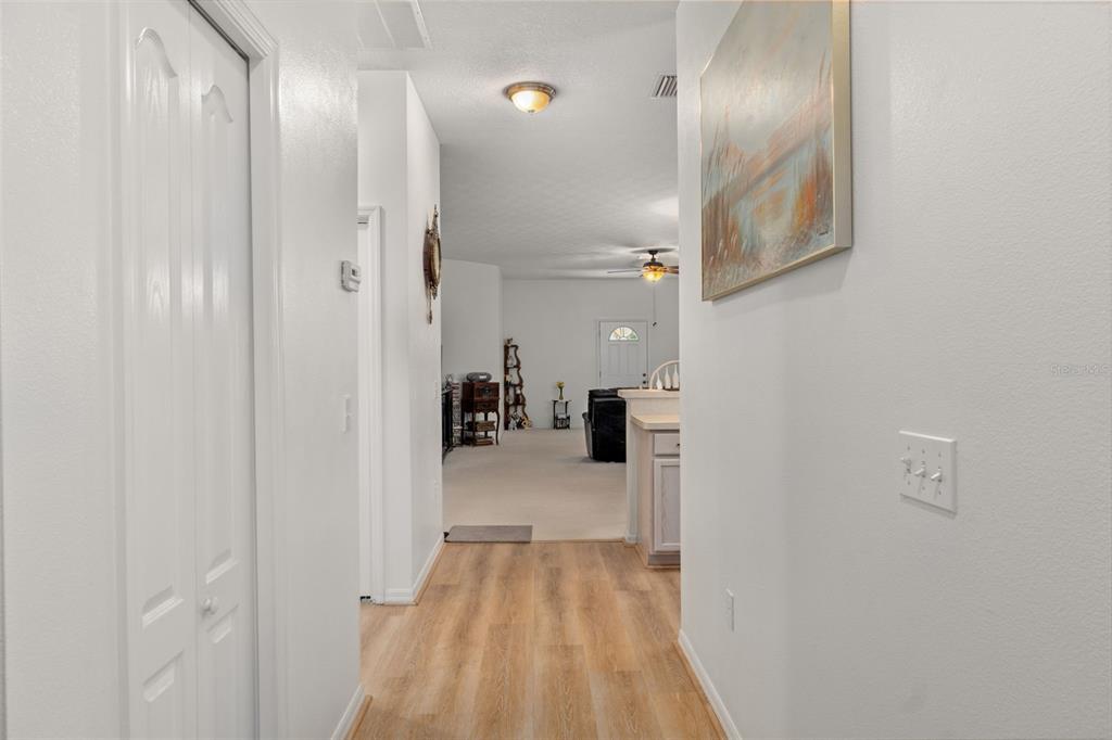 A hallway with wood-look flooring leads into a carpeted living area with a ceiling fan — 6531 W CANNONDALE DRIVE, CRYSTAL RIVER, FL