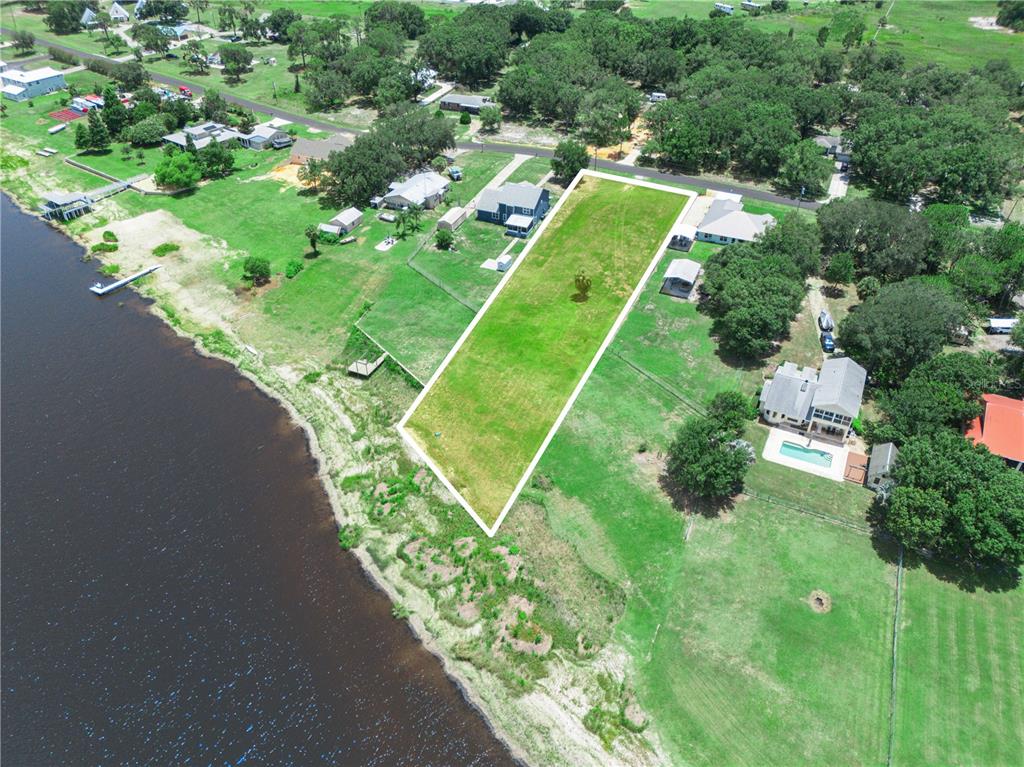 An aerial view shows a rectangular vacant lot bordering a lake in a residential area — 860 KEEN ROAD, FROSTPROOF, FL