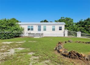 A light-colored single-story manufactured home sits on a grassy lot under a clear blue sky — 4555 Pioneer 16th St, Clewiston FL 33440, CLEWISTON, FL