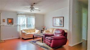 A living room features a red armchair, a light-colored sofa, and a ceiling fan — 4555 Pioneer 16th St, Clewiston FL 33440, CLEWISTON, FL