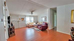 A living room with wood-look flooring, a ceiling fan, and a red leather armchair — 4555 Pioneer 16th St, Clewiston FL 33440, CLEWISTON, FL
