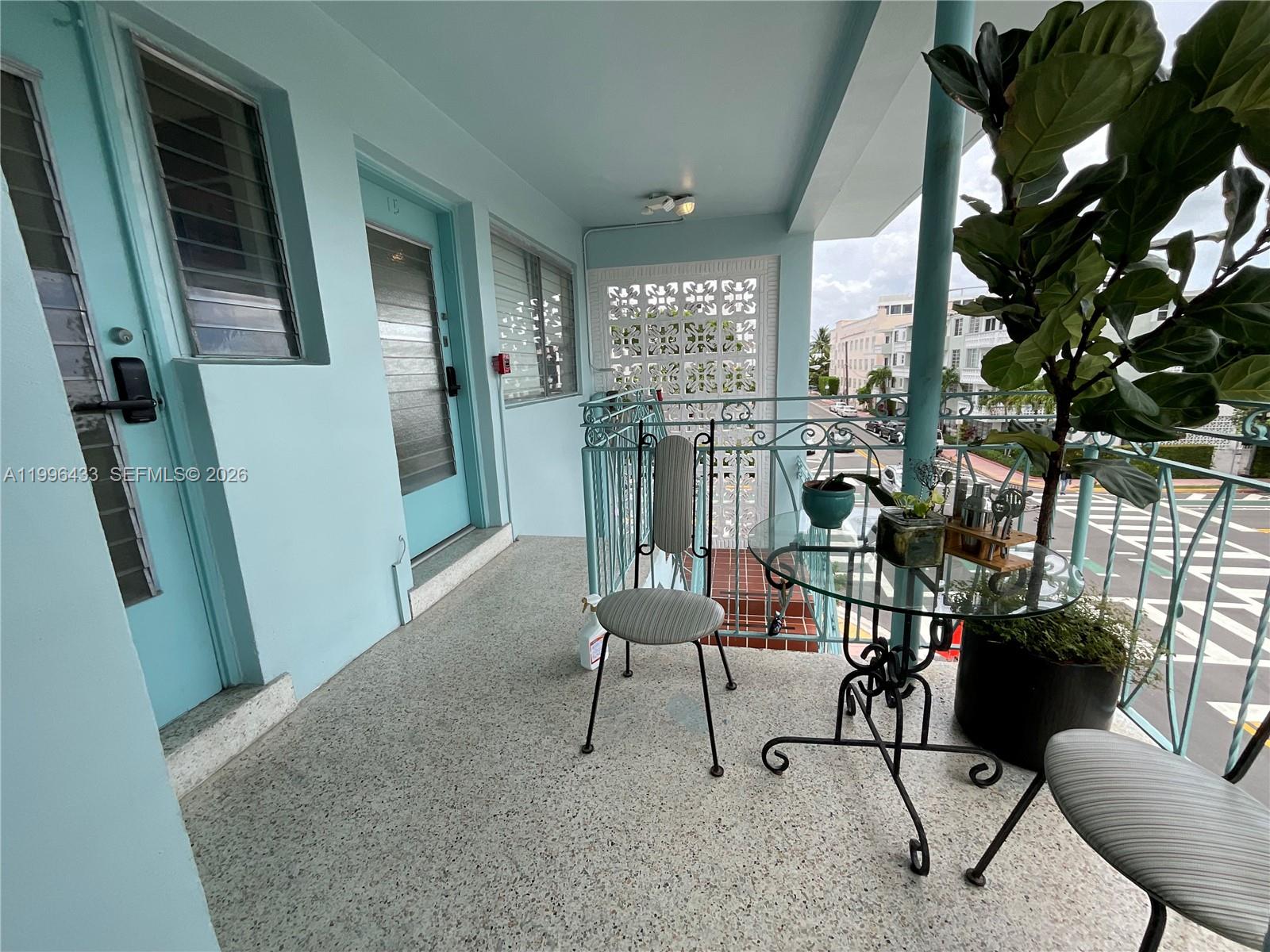 A light blue balcony features a glass-topped table, two chairs, and a potted plant — 1004 Pennsylvania Ave # 15, Miami Beach FL 33139, MIAMI BEACH, FL