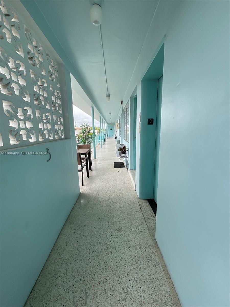 An outdoor walkway with light blue walls, a speckled floor, and a decorative screen wall — 1004 Pennsylvania Ave # 15, Miami Beach FL 33139, MIAMI BEACH, FL