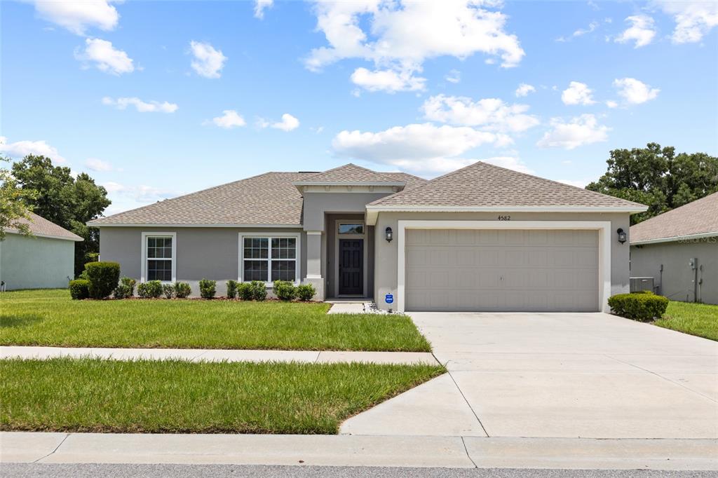 A single-story house with a gray stucco exterior, a two-car garage, and a front lawn — 4582 PENKERT PLACE, LAKELAND, FL