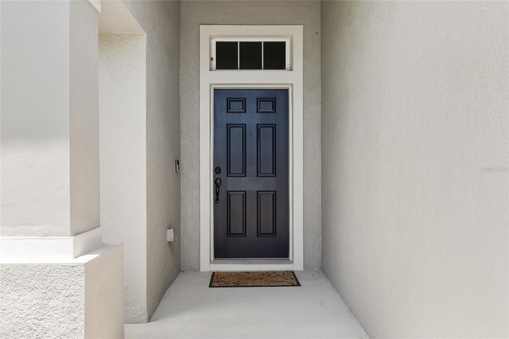 A dark blue front door with a transom window sits in a recessed entryway — 4582 PENKERT PLACE, LAKELAND, FL