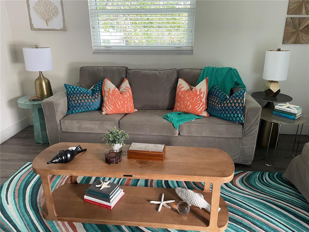 A living room features a gray sofa, a wooden coffee table, and coastal-themed decor — 1910 MORRILL STREET UNIT 1, SARASOTA, FL