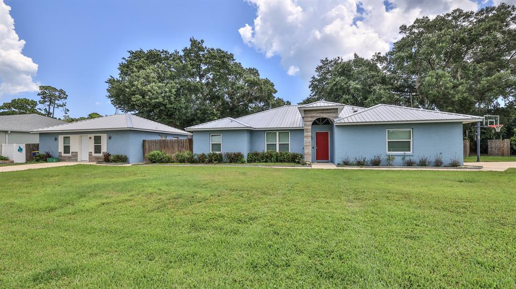 A blue single-story house with a metal roof and a red front door — 2773 DATE PALM DRIVE, EDGEWATER, FL