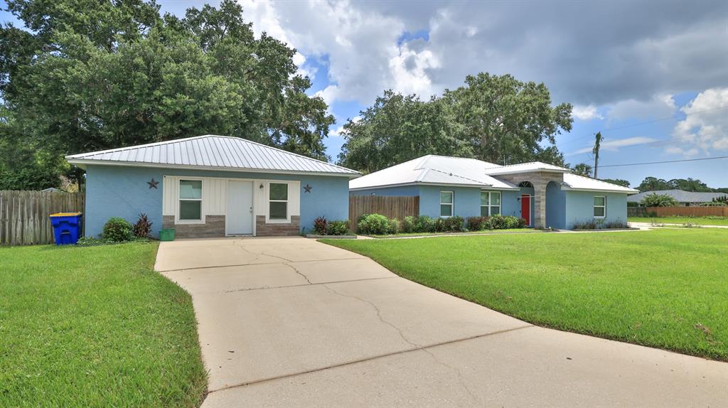 A blue house with a metal roof and a concrete driveway sits on a lawn — 2773 DATE PALM DRIVE, EDGEWATER, FL