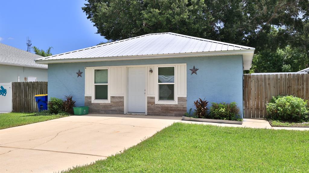 A single-story blue house with a metal roof, white trim, and a concrete driveway — 2773 DATE PALM DRIVE, EDGEWATER, FL