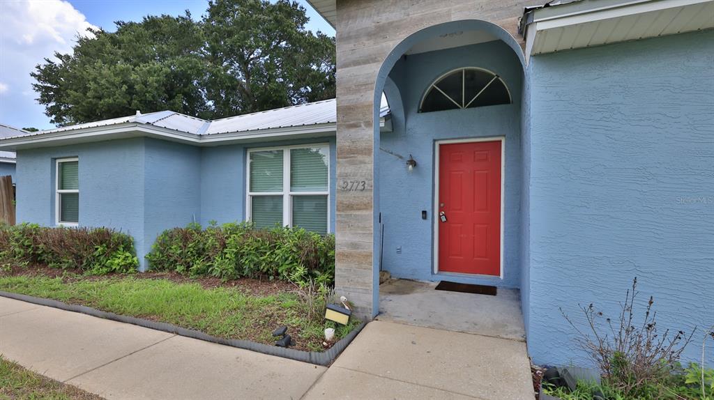 A blue house with a red front door and a stone-accented entryway — 2773 DATE PALM DRIVE, EDGEWATER, FL