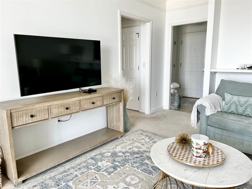 A living room features a television on a wooden console, a rug, and a sofa — 750 N TAMIAMI TRAIL UNIT 708, SARASOTA, FL