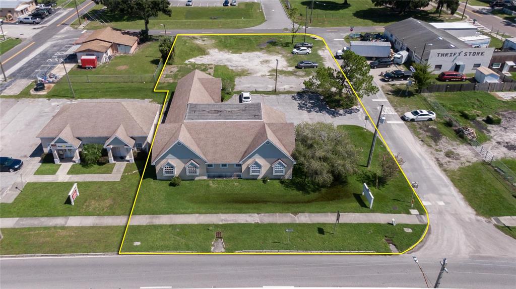 An aerial view shows a commercial building with a tan exterior and a large parking lot — 504 E BAKER STREET, PLANT CITY, FL