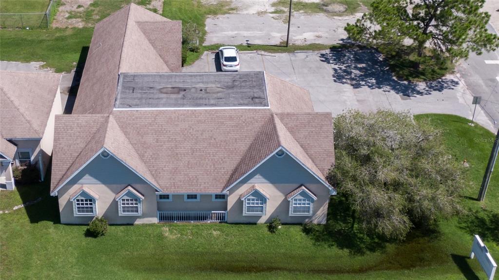 An aerial view shows a tan building with a brown shingled roof and parking lot — 504 E BAKER STREET, PLANT CITY, FL