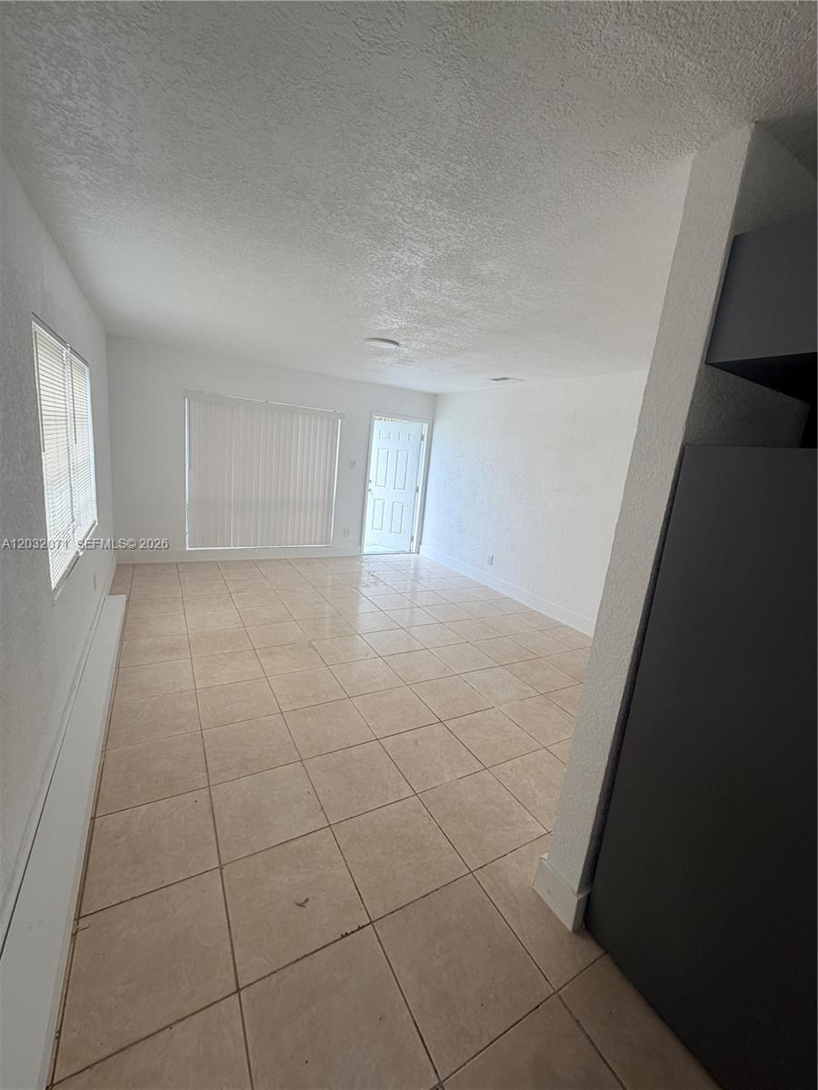 An empty room features white walls, a tiled floor, vertical blinds, and a glass door — 753 SW 3rd Pl # 753, Dania Beach FL 33004, DANIA BEACH, FL