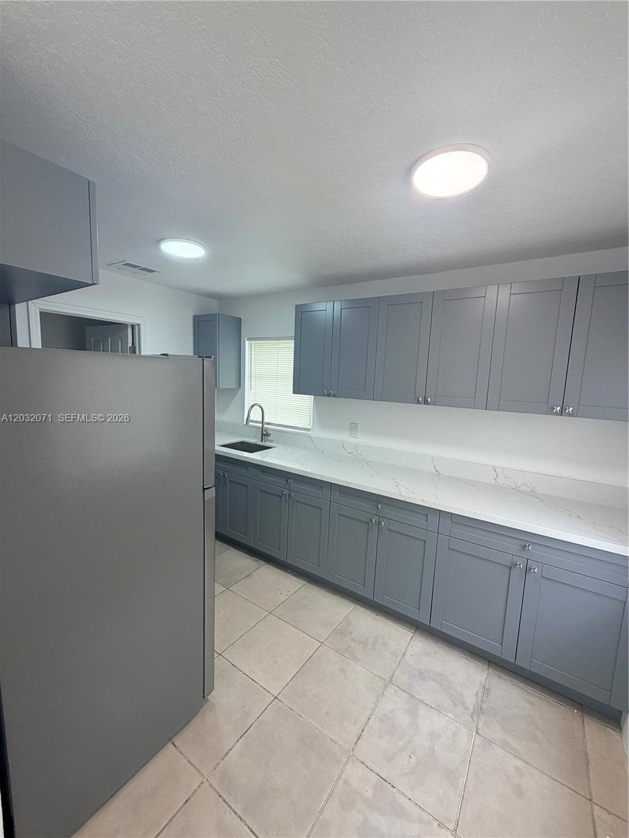 A kitchen features gray cabinets, white marble-patterned countertops, and light-colored tile flooring — 753 SW 3rd Pl # 753, Dania Beach FL 33004, DANIA BEACH, FL