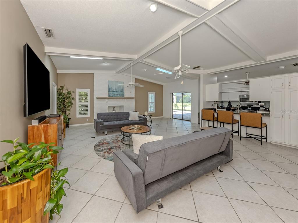 A living room with tile floors, a white brick fireplace, and an open kitchen area — 750 SHETLAND CIRCLE, NOKOMIS, FL