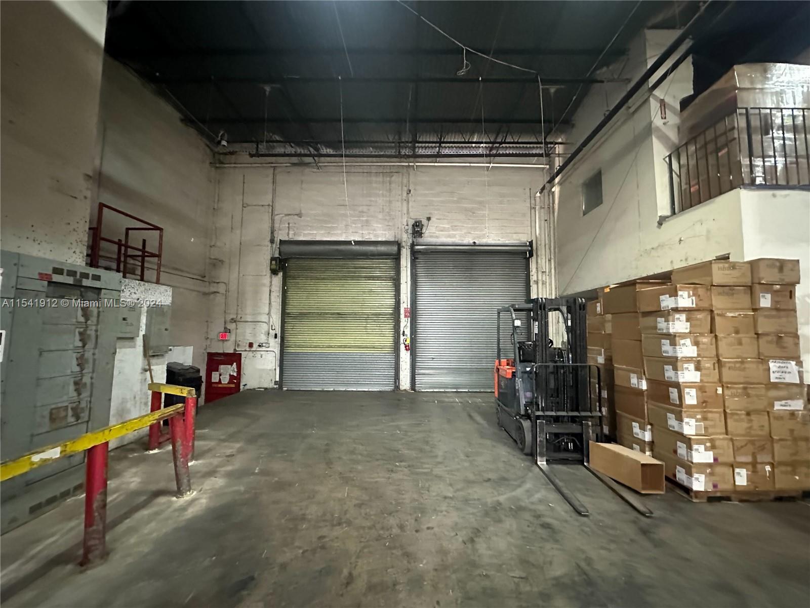 An industrial warehouse interior features two roll-up doors, a forklift, and stacked cardboard boxes — 13449 NW 42nd Ave, Opa-Locka FL 33054, OPA-LOCKA, FL