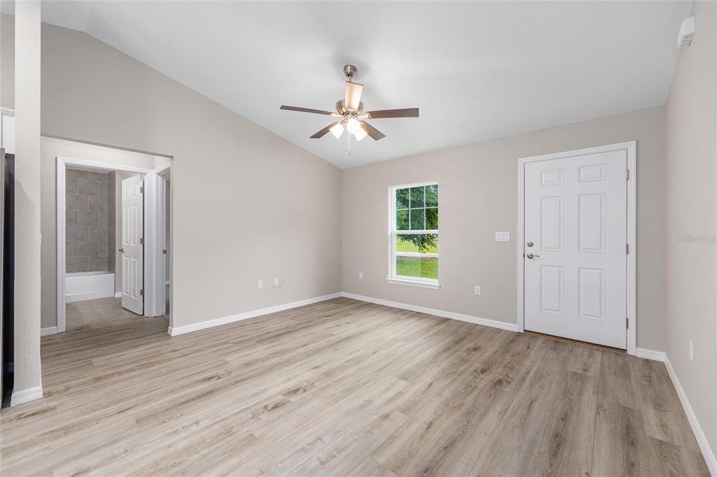 An empty room with light wood-look flooring, a ceiling fan, and an attached bathroom — 14719 SW 23RD PLACE, OCALA, FL
