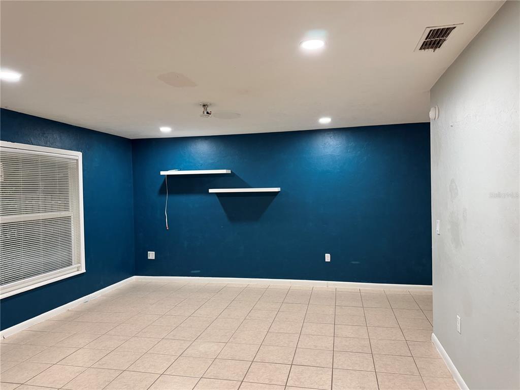 A room with blue walls, tiled flooring, two floating shelves, and a window with blinds — 2003 NW 31ST AVENUE, GAINESVILLE, FL