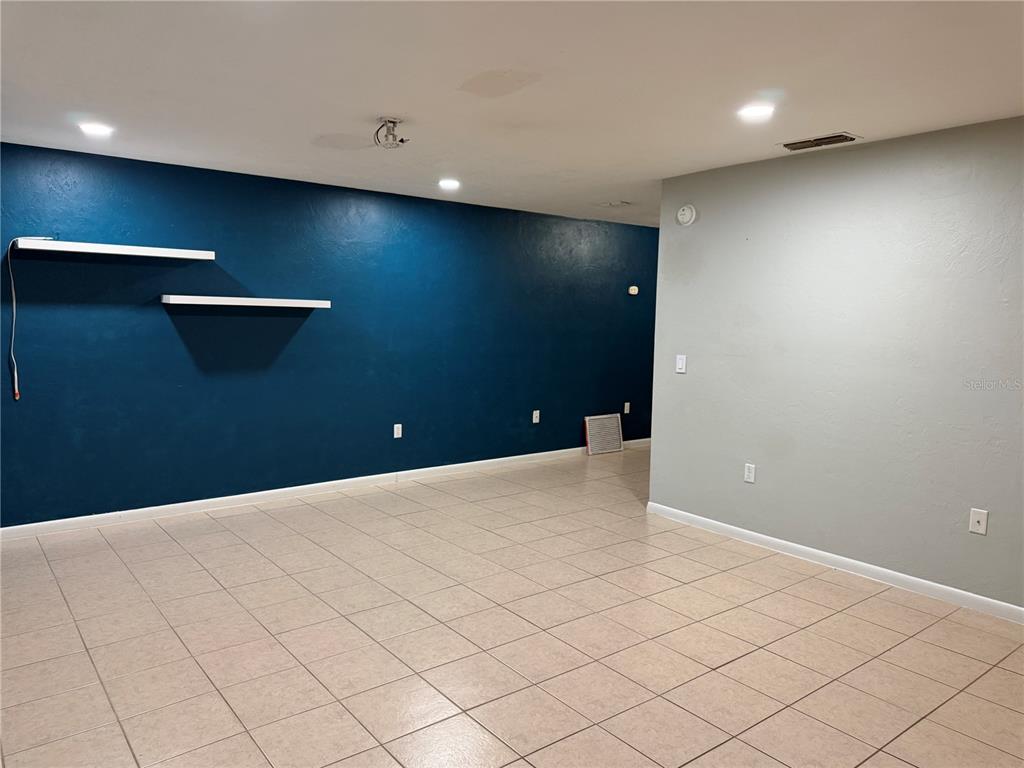 A room with light-colored tile flooring, a dark blue accent wall with shelves, and gray walls — 2003 NW 31ST AVENUE, GAINESVILLE, FL