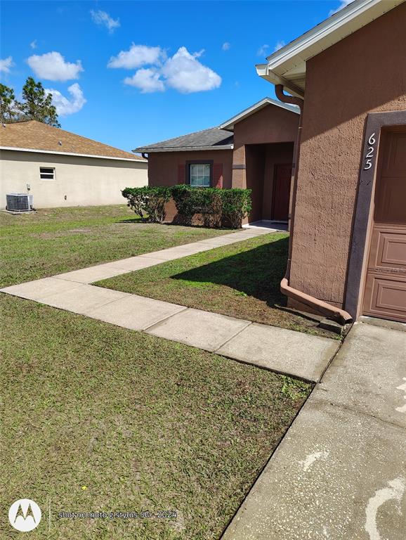 A brown stucco house features a concrete walkway leading to the front entrance — 625 S DELMONTE COURT, KISSIMMEE, FL