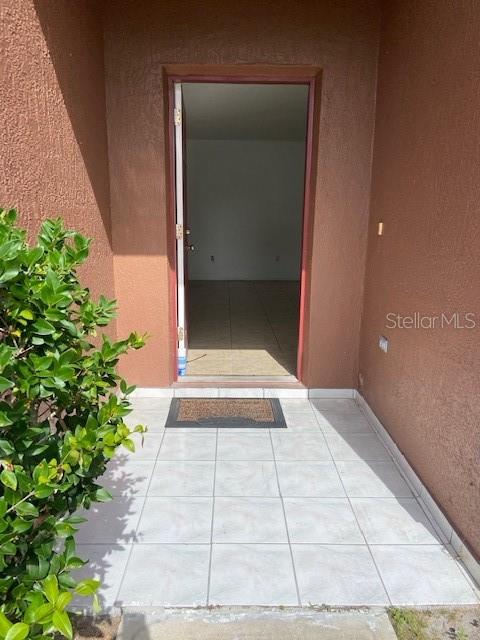 A tiled entryway leads through an open doorway into an empty room with tiled floors — 625 S DELMONTE COURT, KISSIMMEE, FL