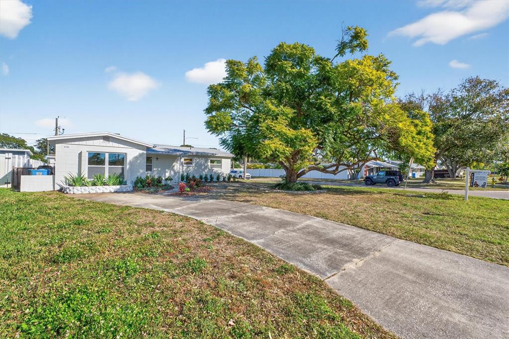 A single-story house with a concrete driveway and a large tree in the front yard — 5701 14TH AVENUE N, ST PETERSBURG, FL