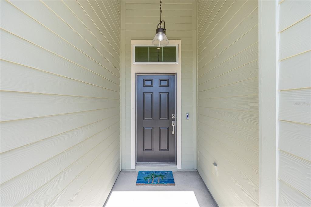 A dark gray front door with a transom window is set in a covered entryway — 7834 SW 194TH COURT, DUNNELLON, FL