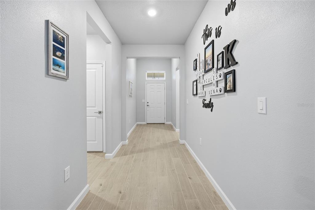 A bright hallway features light wood-look tile flooring, white walls, and a white front door — 7834 SW 194TH COURT, DUNNELLON, FL