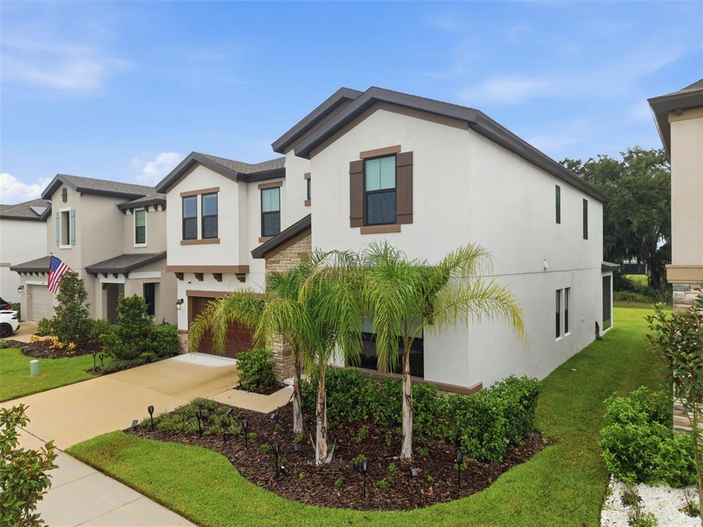 A two-story suburban house with a stucco exterior, palm trees, and a concrete driveway — 14759 GALLOP RUN DRIVE, LITHIA, FL