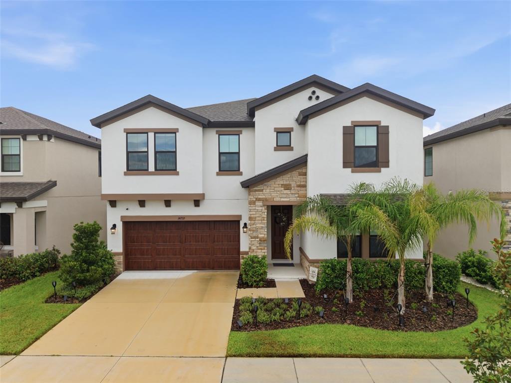 A two-story house with a white stucco facade, stone accents, and a two-car garage — 14759 GALLOP RUN DRIVE, LITHIA, FL
