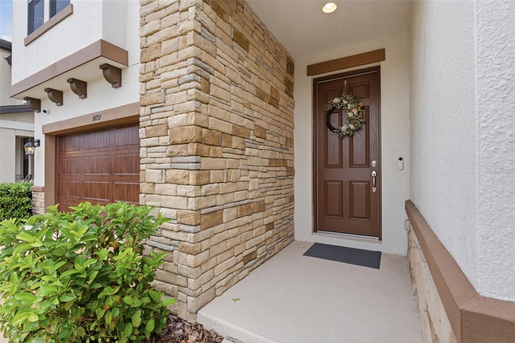A stone-accented entryway features a brown front door with a wreath and a garage — 14759 GALLOP RUN DRIVE, LITHIA, FL