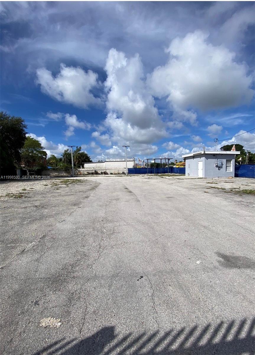 A large, paved vacant lot features a small, gray utility building under a cloudy sky — 300 NW 79th St, Miami FL 33150, MIAMI, FL
