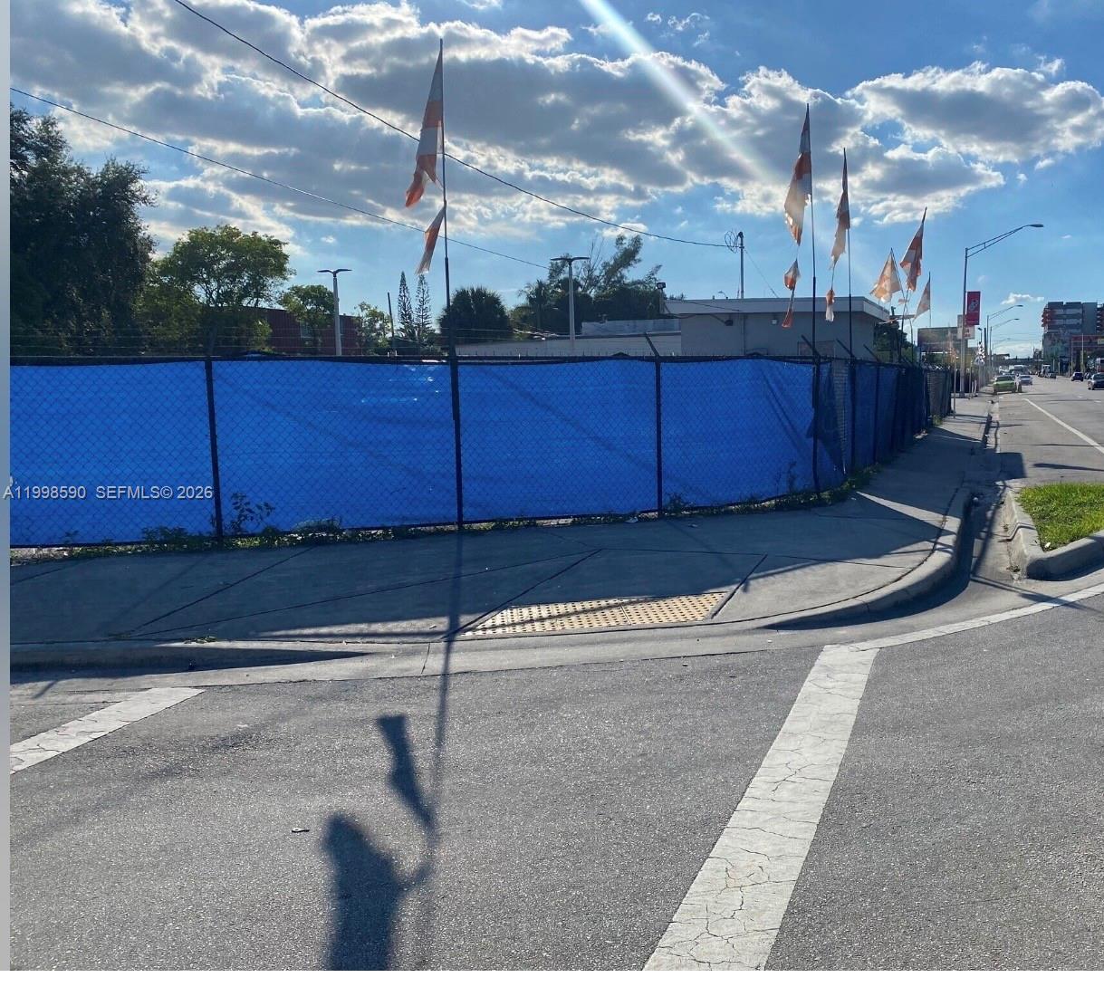A fenced-in vacant lot sits at a street corner with several decorative flags — 300 NW 79th St, Miami FL 33150, MIAMI, FL