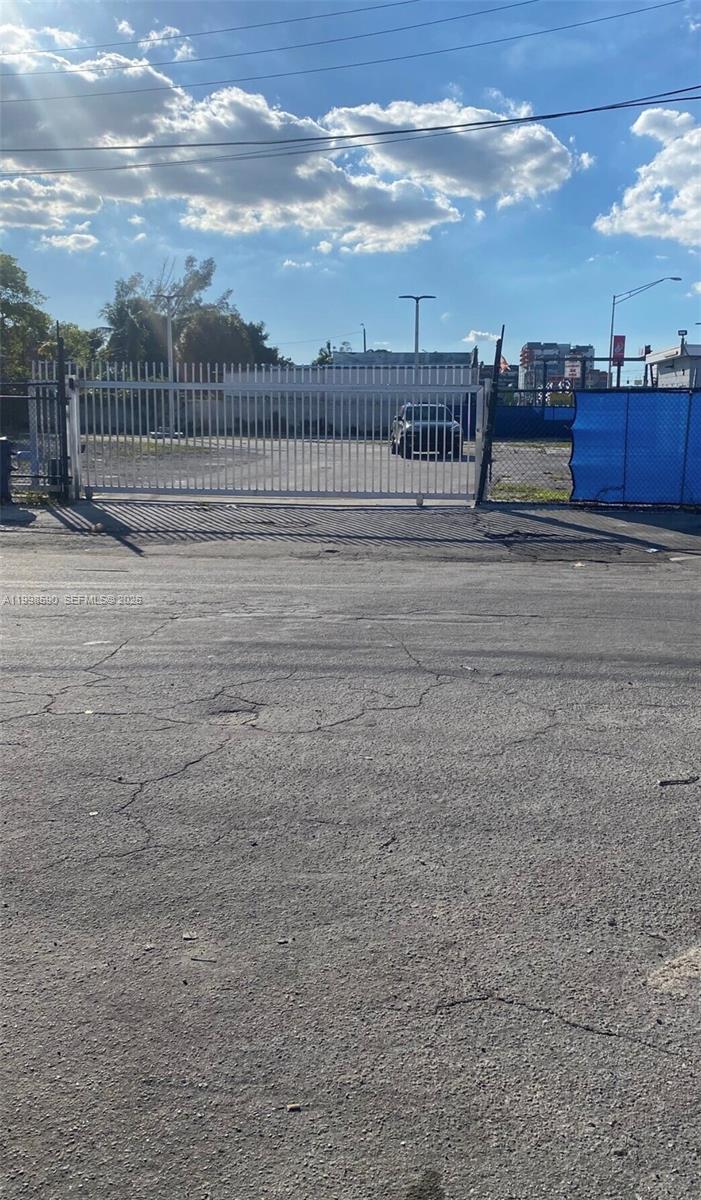 A gated entrance leads to an empty, paved lot under a blue sky — 300 NW 79th St, Miami FL 33150, MIAMI, FL