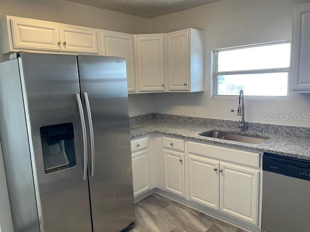 A kitchen features white cabinets, granite countertops, a stainless steel refrigerator, and a sink — 221 W EMILY STREET, TAMPA, FL