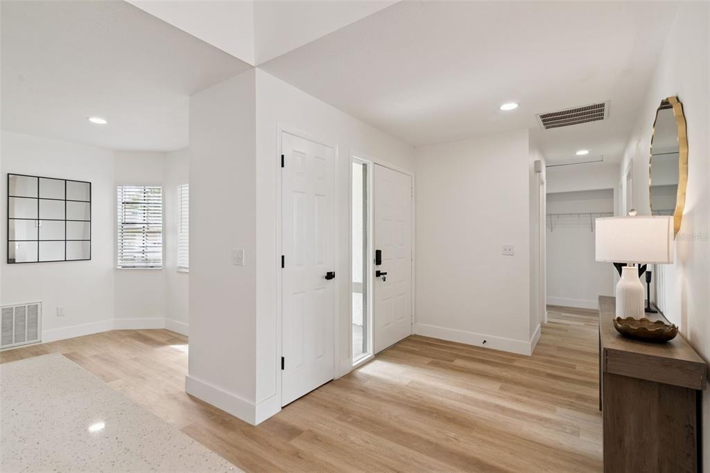 An entryway with light wood flooring, white walls, a front door, and a console table — 13132 PHOENIX WOODS LANE, ORLANDO, FL