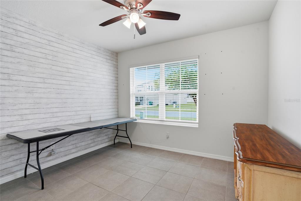 A room with a shiplap accent wall, a folding table, and a wooden dresser — 35803 HILLBROOK AVENUE, ZEPHYRHILLS, FL